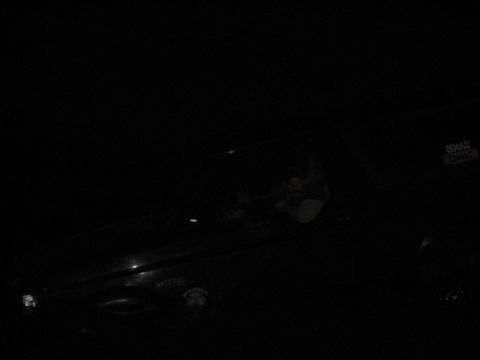 1995 Ford Bronco - A dark SUV is barely visible in this dimly lit scene, with a sticker on its rear window.