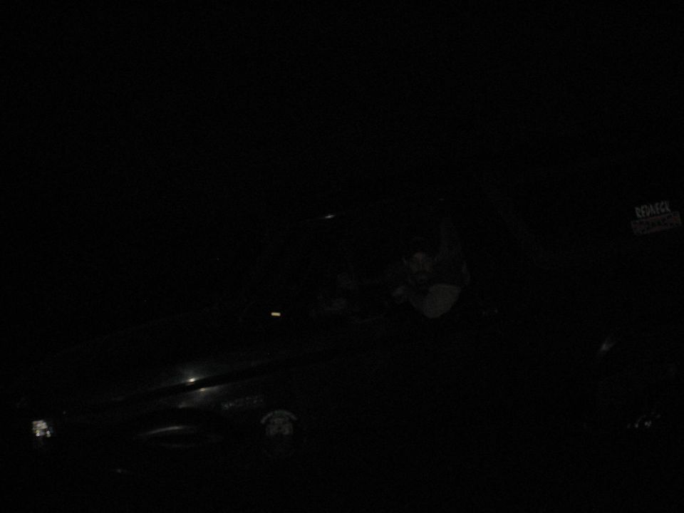 Underexposed night photo of a dark SUV with a person at the window and a Redneck window sticker
