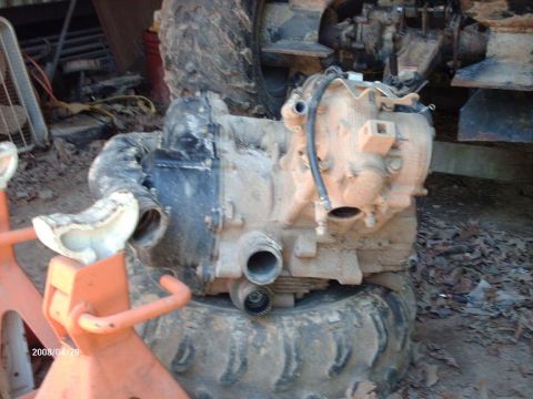 1990 Ford F-150 - A muddy engine component is supported by orange jack stands, with a tire underneath.