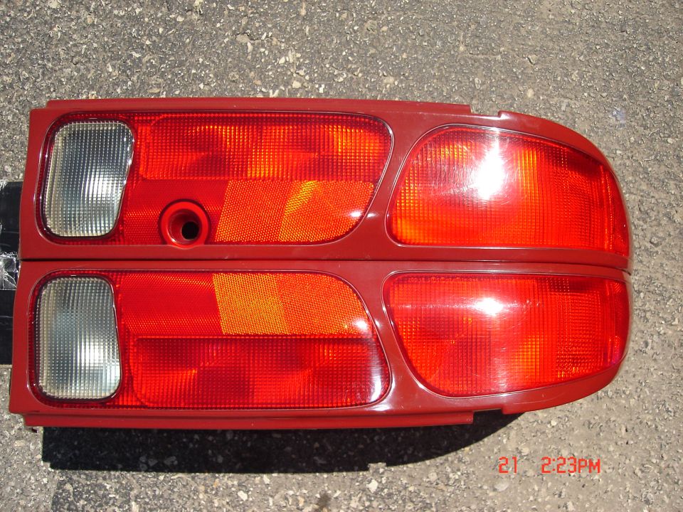 Two red taillights with clear turn signal sections, laid out on a gray surface
