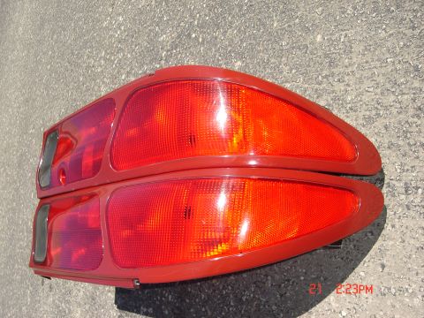 1993 Ford Probe - Two red tail lights are shown from a rear angle, resting on a textured gray surface.