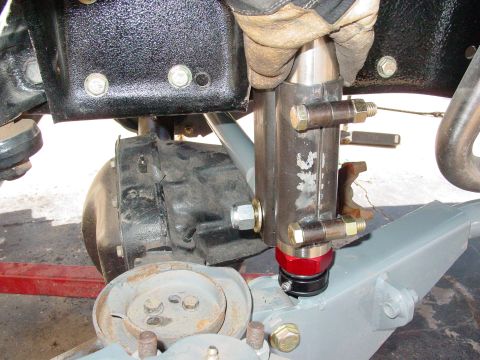 1979 Ford Bronco - A gloved hand installs a shock absorber onto the front suspension of a vehicle.