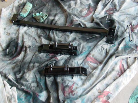 1979 Ford Bronco - Several black painted vehicle suspension parts are arranged on a cloth, suggesting preparation for installation or repair.