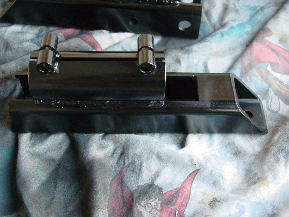 Black metal suspension component with two silver cylindrical pins welded to the top
