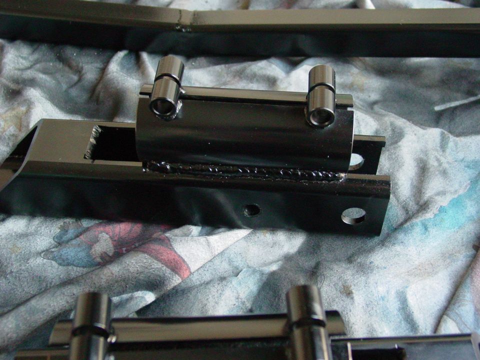 Black metal suspension part with two cylindrical pins, on a patterned cloth