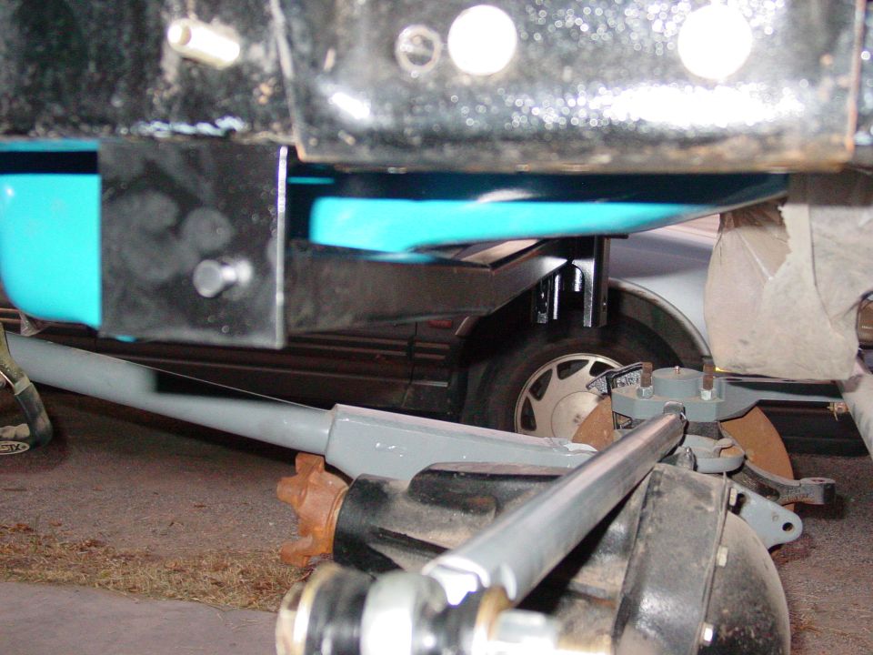 Close-up of a vehicle's front suspension components, including a grey control arm and differential