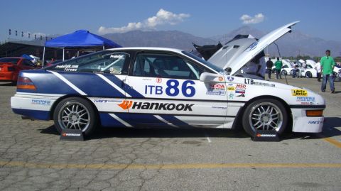 1990 Ford Probe - A race car with Hankook tires and various sponsor decals sits on display with its hood open.