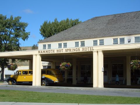 1998 BMW R1100GS ABS - A vintage yellow and black car is parked in front of the Mammoth Hot Springs Hotel.