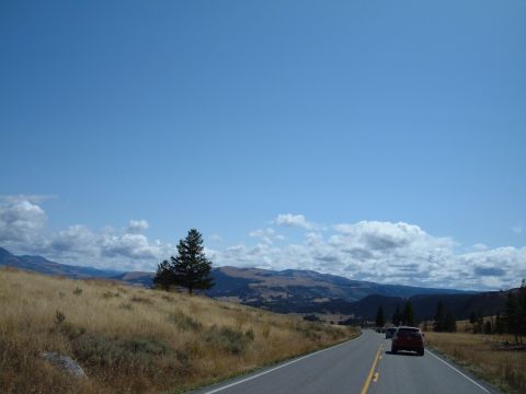 1998 BMW R1100GS ABS - A red SUV travels down a highway through a scenic landscape with mountains and dry grass.