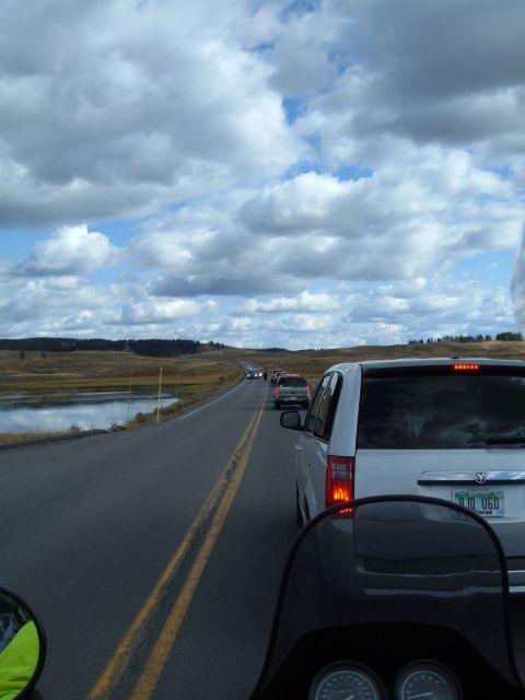 1998 BMW R1100GS ABS - A line of vehicles is stopped on a road with a cloudy sky and a lake nearby.