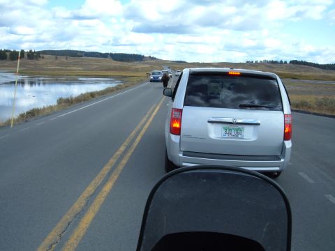 1998 BMW R1100GS ABS - A silver minivan drives down a road with a lake on the left and other vehicles ahead.