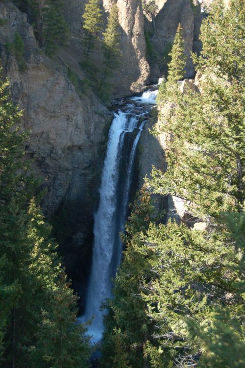 1998 BMW R1100GS ABS - A tall waterfall plunges into a gorge, framed by cliffs and dense evergreen trees.