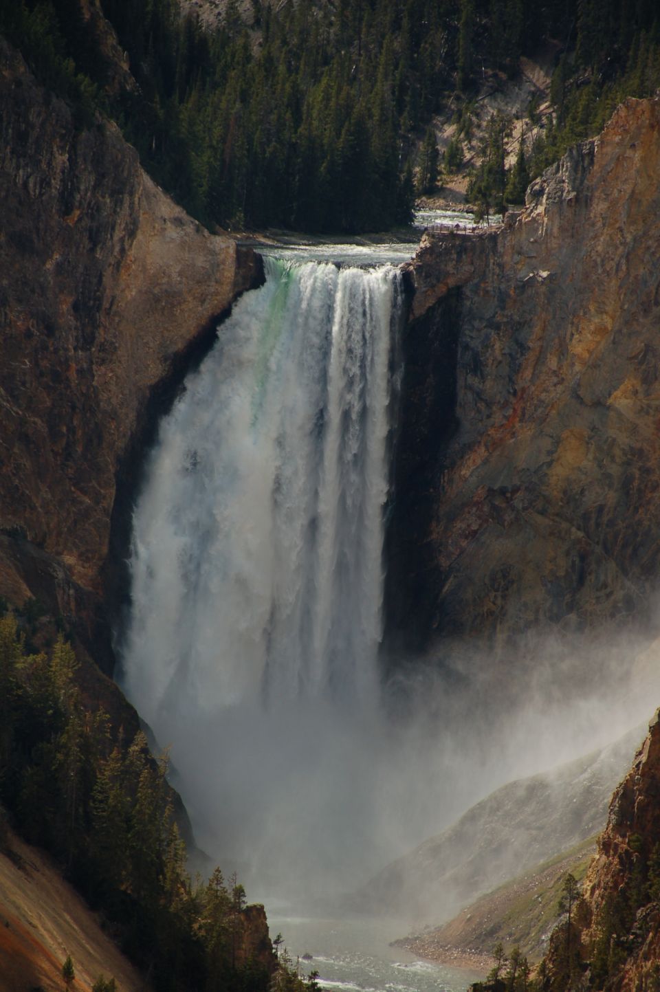 Waterfall cascading into a misty canyon with trees on the cliffs