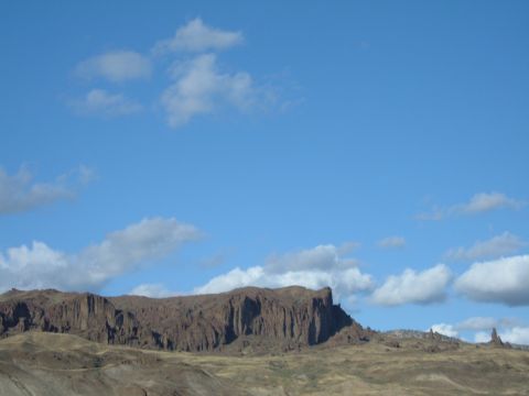 1998 BMW R1100GS ABS - A vast landscape of mountains and a bright blue sky with fluffy clouds, a website watermark.