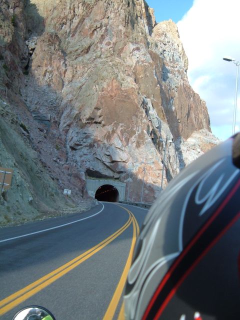 1998 BMW R1100GS ABS - A motorcycle approaches a tunnel on a winding road through a mountainous landscape.