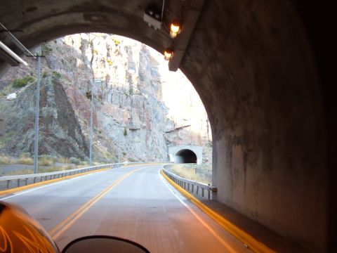 1998 BMW R1100GS ABS - View from a motorcycle exiting a tunnel onto a winding mountain road with rocky cliffs.