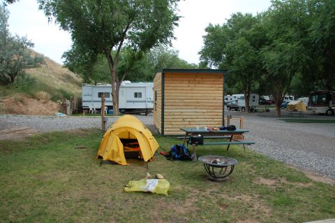 1998 BMW R1100GS ABS - A campsite scene shows a tent set up near a picnic table and fire pit, with RVs parked in the background.