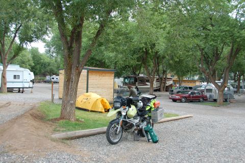 1998 BMW R1100GS ABS - A motorcycle is parked at a campsite, surrounded by tents, RVs, and trees.