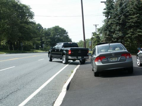2001 Mercury Grand Marquis - Two vehicles parked on the side of a road with trees and utility poles in the background.