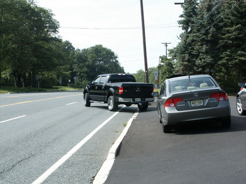Black pickup truck parked on shoulder next to a gray Honda Civic sedan