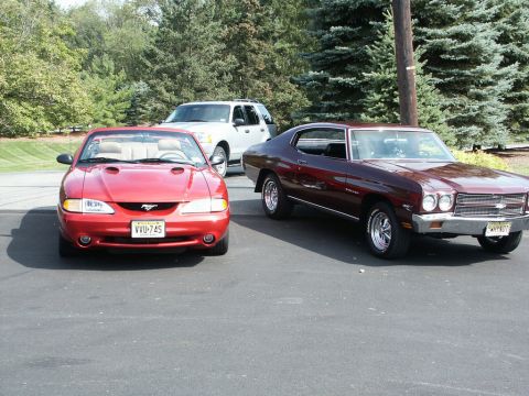 2001 Mercury Grand Marquis - A red convertible sports car is parked in front of a white SUV and a maroon coupe.