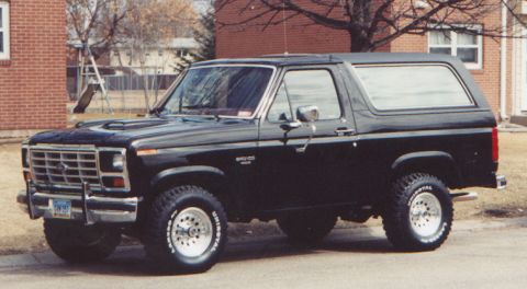 1986 Ford Bronco - This black Ford Bronco, likely from the early 1980s, is shown from a three-quarter front angle.