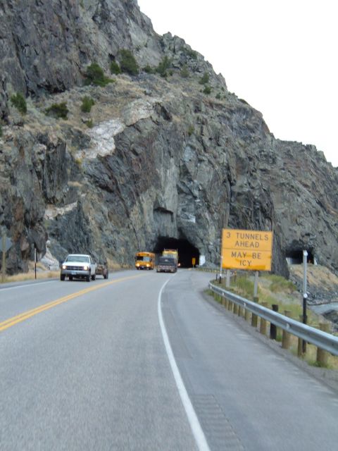 1998 BMW R1100GS ABS - A road curves towards a tunnel entrance, with a sign warning of upcoming tunnels and icy conditions.