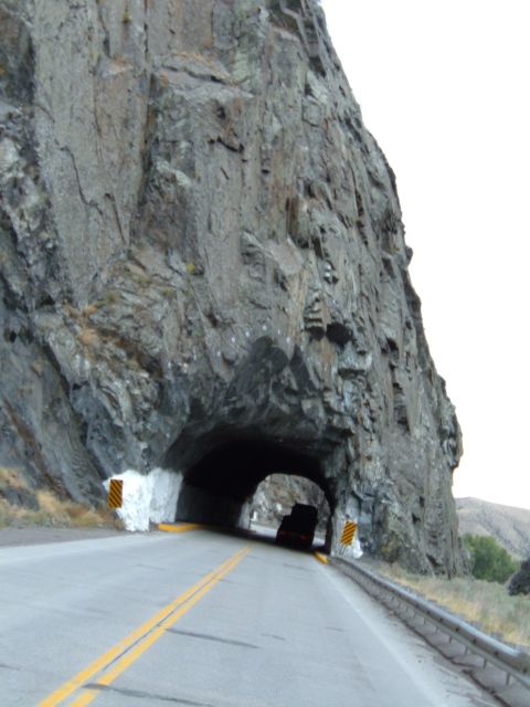 1998 BMW R1100GS ABS - A road leads into a tunnel through a large rock formation, with a single vehicle ahead.
