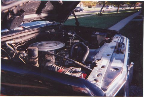 1986 Ford Bronco - The engine compartment of a vehicle is shown with various components including the air cleaner and hoses.