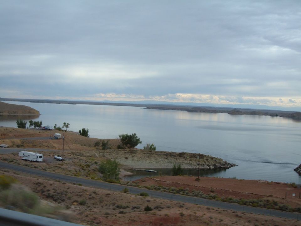 RV and car parked near a lake with a cloudy sky