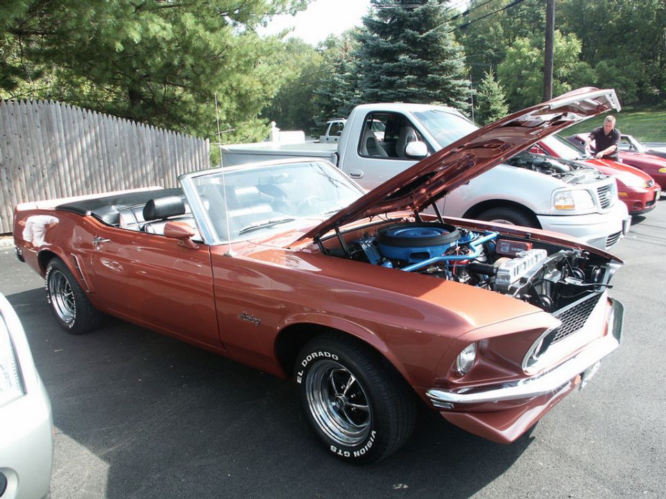 1969 Ford Mustang convertible with hood open, showing engine. Other vehicles visible behind