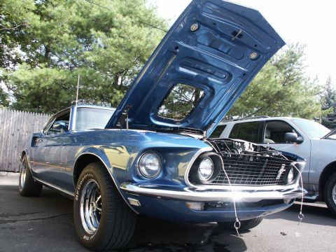 2001 Mercury Grand Marquis - A blue 1969 Ford Mustang is displayed with its hood open, revealing the engine, next to an SUV.