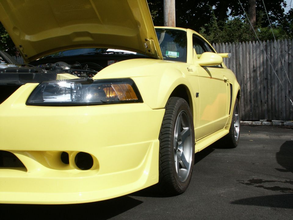 Yellow Ford Mustang with hood open, front quarter view