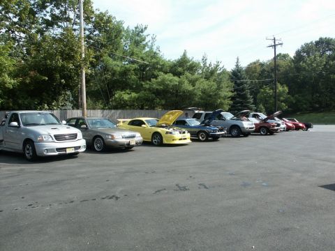 2001 Mercury Grand Marquis - A variety of vehicles are lined up in a parking lot, with several hoods open, suggesting a car show or gathering.