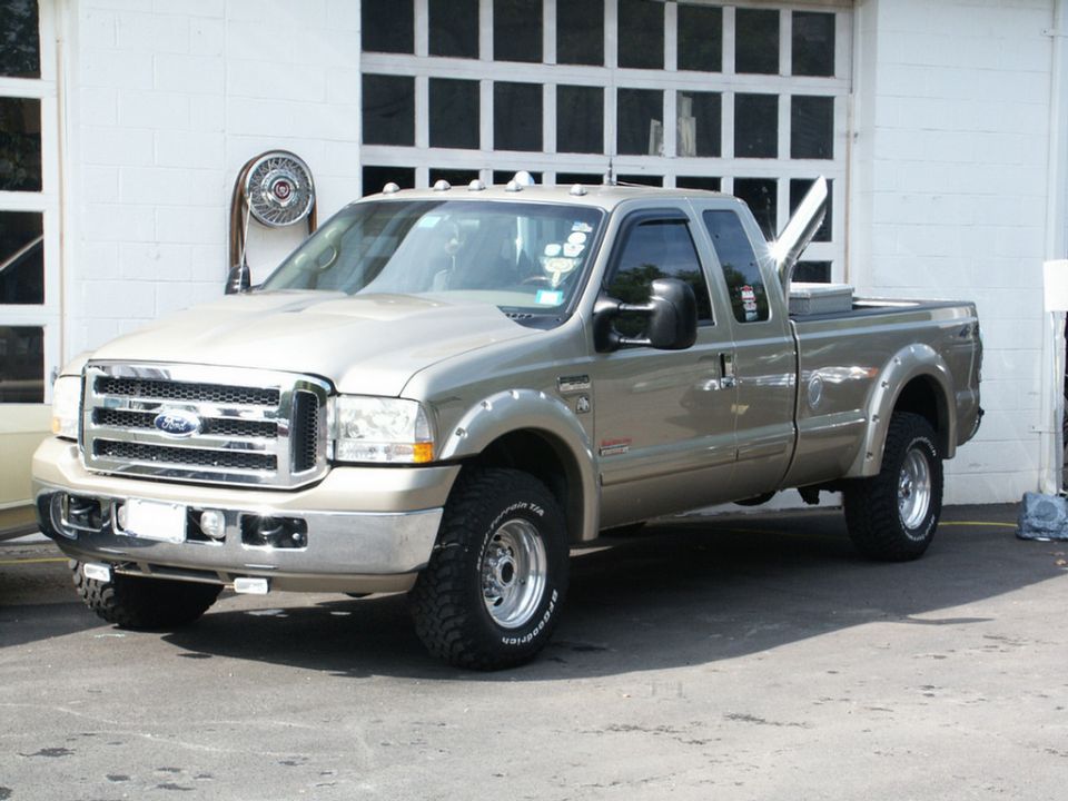 Tan Ford F-250 pickup truck parked in front of a garage door. It has a chrome grille and fender flares