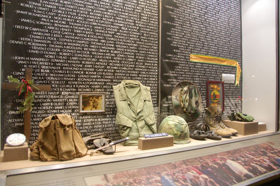Display case with Vietnam Veterans Memorial wall, military uniform, helmet, boots, and backpack
