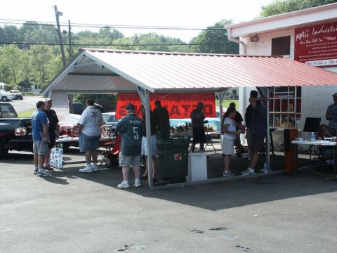 2001 Mercury Grand Marquis - People gather at an outdoor car show under a red-roofed tent, with a banner and tables visible.