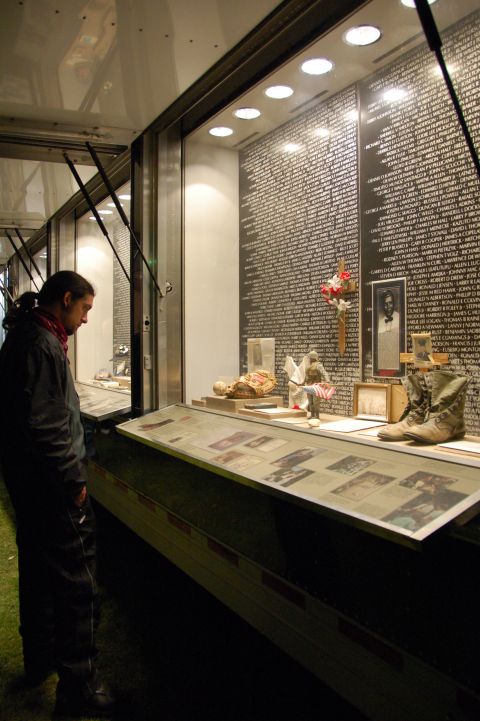 1998 BMW R1100GS ABS - A person observes a memorial exhibit names, a boot, and various artifacts behind glass.