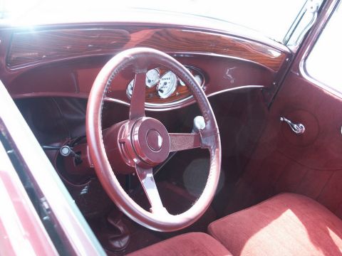 2001 Mercury Grand Marquis - The interior of a classic car features a maroon steering wheel, woodgrain dashboard, and matching upholstered seats.