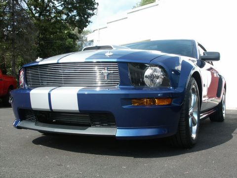 2001 Mercury Grand Marquis - A blue Ford Mustang with white racing stripes is parked outside on a sunny day.