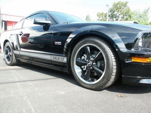 2001 Mercury Grand Marquis - A black Ford Mustang Shelby GT is parked on asphalt, showing its side profile and front wheel.
