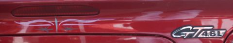 2001 Mercury Grand Marquis - A red car's rear with custom pinstriping and a GT 4.6L emblem is visible.