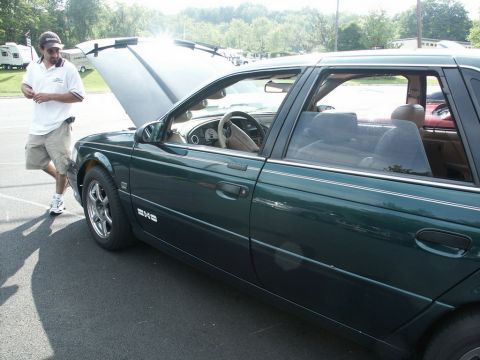 2001 Mercury Grand Marquis - A man stands by a dark green 2001 Mercury Grand Marquis with its hood open at a car show.