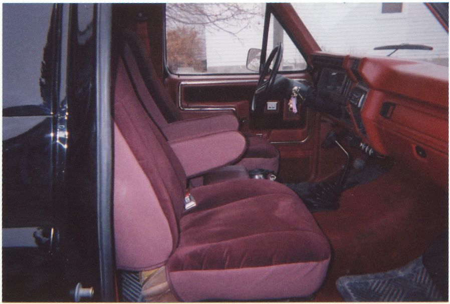 Maroon cloth bench seats and red dashboard interior of a Ford truck