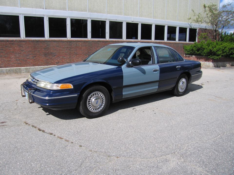 Two-tone Ford Crown Victoria, blue and light blue, parked outside a building