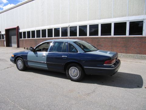 2001 Ford Crown Victoria - A two-tone blue 2001 Ford Crown Victoria is parked outside a commercial building.