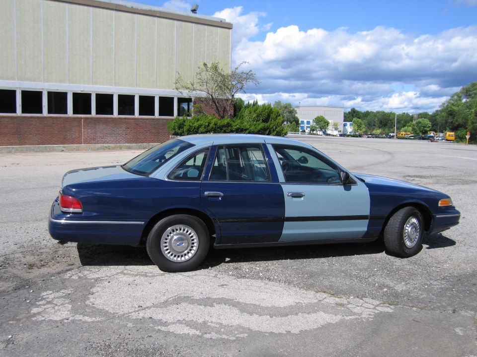 Two-tone blue Ford Crown Victoria sedan, driver-side profile view