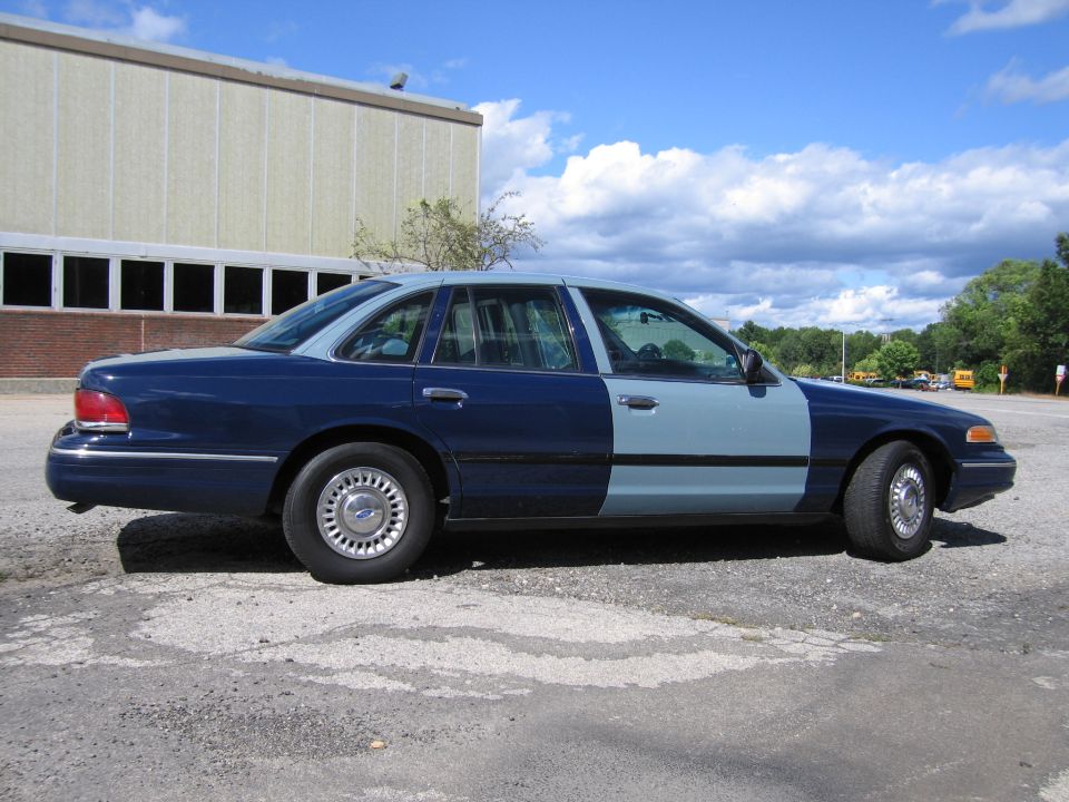 Two-tone blue Ford Crown Victoria sedan, passenger-side profile view
