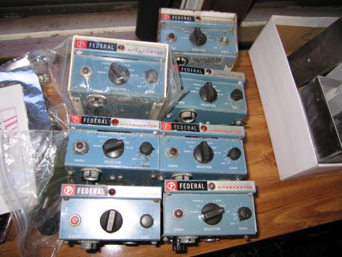 1991 Ford LTD Crown Victoria - collection of vintage blue Federal Interceptor siren control units with dials and switches arranged on a wooden bench.
