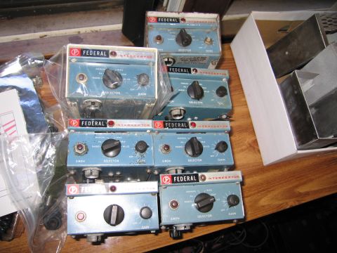 1991 Ford LTD Crown Victoria - Multiple vintage Federal Interceptor siren control boxes with labeled knobs and switches displayed on a wooden surface.